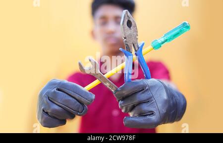 Mechaniker mit Werkzeug auf verschwommenem Hintergrund. Nahaufnahme des metallischen Reparaturmannes Strong Fist Holding Schraubenschlüssel Stockfoto
