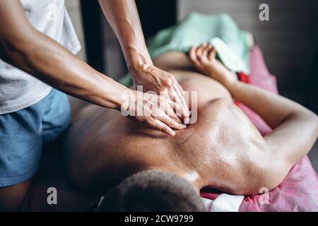 Eine Frau Physiotherapeutin, die eine Rückenmassage für einen Mann in der Arztpraxis macht. Nahaufnahme der Hände beim Massieren. Stockfoto