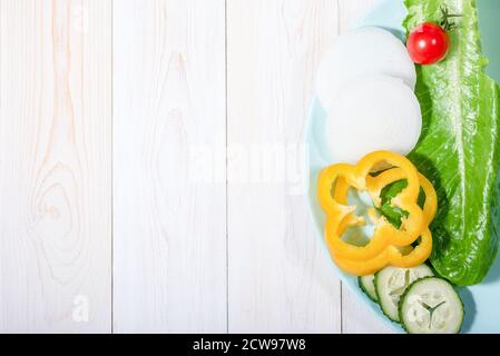 Vegetarische Frischmischung - grüner Salat, Zwiebelringe, Kirschtomaten, Paprika und Gurke. Rohe Zutaten für Gemüsegericht Stockfoto