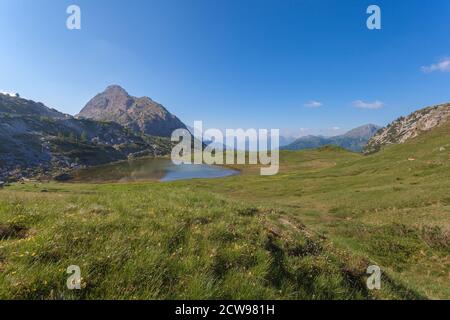 Valparolasee eingebettet in die Mitte von Wiesen mit der typischen Dolomitenlandschaft im Hintergrund, Valparola Pass, Dolomiten, Italien Stockfoto