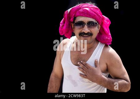 Mode Kleidung ein Mann trägt einen rosa Kopfschmuck mit einem Lächeln Sie auf seinem Gesicht auf einem schwarzen Hintergrund Stockfoto