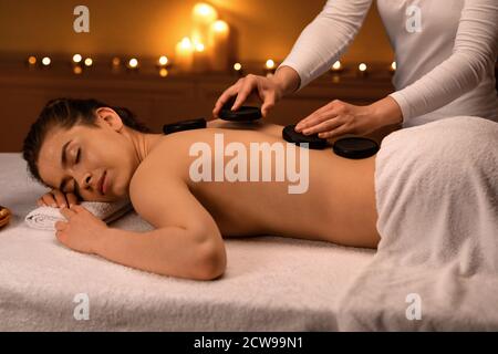 Entspannte Dame mit Hot Stone Massage im modernen Spa Stockfoto
