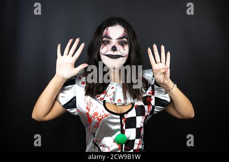 Frau in einem halloween Clown Kostüm über isoliertem schwarzem Hintergrund Zeigen und zeigen mit den Fingern Nummer neun beim Lächeln Selbstbewusst und glücklich Stockfoto