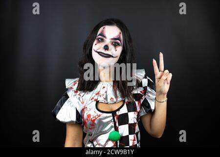 Frau in einem halloween Clown Kostüm über isoliertem schwarzem Hintergrund Zeigen und zeigen mit den Fingern Nummer zwei beim Lächeln Selbstbewusst und glücklich Stockfoto