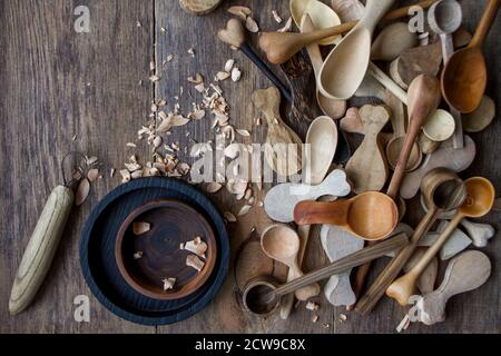 Handgemachte Küchengeräte aus Holz, Draufsicht viele Knüppel, Löffel und Teller auf Holztisch, selektiver Fokus Stockfoto