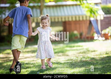 Kleiner Junge und kleines Mädchen spielen im Freien am Sommertag Stockfoto