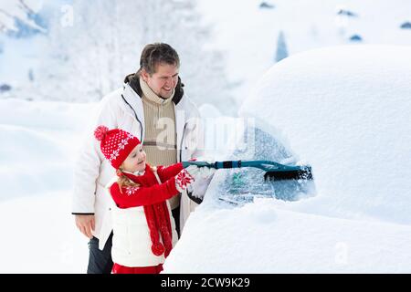 Vater und Kind Bürsten und Schneeschaufeln off-Auto nach Sturm. Eltern und Kind mit Winter Bürste und Schaber clearing Familie Auto nach Übernachtung sno Stockfoto