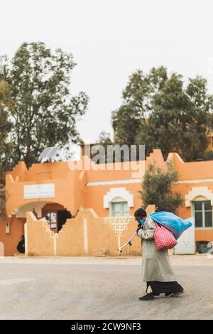 MARRAKESCH, MAROKKO - 10. SEPTEMBER 2019: Armer, obdachloser, einsamer Bettler, der mit riesigen Taschen an der marokkanischen Straße in Marrakesch entlang läuft. Stockfoto