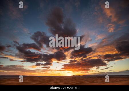 Fantastische helle und bunte Sonnenuntergang über Sanddünen in Sahara Wüste in Marokko. Erstaunliche Wolken und Sonnenlicht. Stockfoto