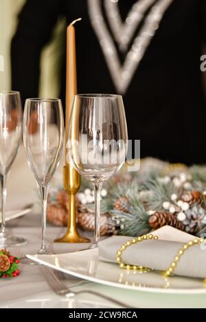 Wählen Sie Fokus von mehreren Gläsern umgeben von schönen Weihnachtsdekorationen und einem Teller auf einem unscharf Hintergrund. Weihnachtsdekoration Konzept. Stockfoto