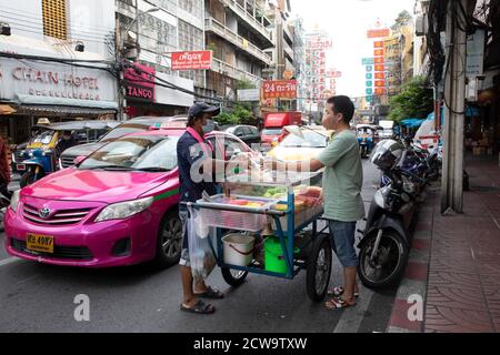 Ein Verkäufer verkauft Obst von seinem Wagen an einen Pendler in Bangkoks Chinatown während der Nachmittagsverkehrszeit. Stockfoto