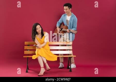 Gitarre spielen im jungen Mann und hören Die Musik junger Frauen Stockfoto