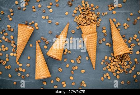 Flaches Kaffee-Eis in Waffelkegel auf dunklem Steinhintergrund. Hausgemachtes Kaffee-Eis mit Kaffeebohnen für Süßigkeiten Menüdesign. Stockfoto