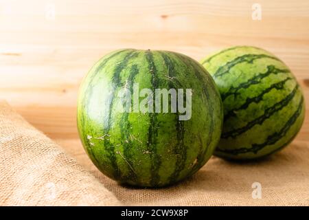 Wassermelone aus nächster Nähe. Zwei reife Bio-Wassermelonen auf rustikalem Holzhintergrund Stockfoto