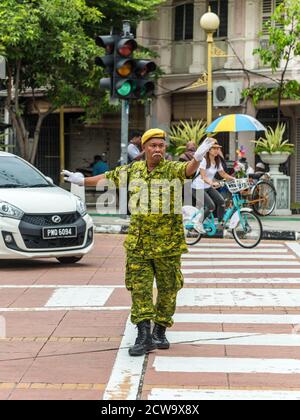 George Town, Penang, Malaysia - 1. Dezember 2019: Straßenverkehrswächter arbeitet an der Kreuzung in George Town, Penang, Malaysia bei bewölktem Wetter. Stockfoto
