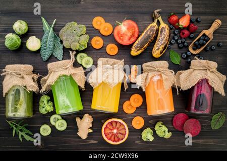 Bunte gesunde Smoothies und Säfte in Flaschen mit frischen tropischen Früchten und Superfoods auf Holz- Hintergrund. Stockfoto