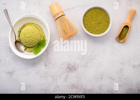 Matcha Grüntee Eis mit Matcha Schneebesen Pinsel Setup auf weißem Stein Hintergrund. Sommer und Süße Menükonzept. Stockfoto