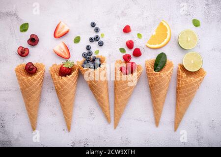 Verschiedene Früchte in Zapfen Heidelbeere, Erdbeere, Himbeeren und Erdbeere Setup auf weißem Stein Hintergrund. Sommer und Süße Menükonzept. Stockfoto