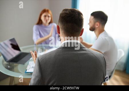 Selbst professionelle Psychologe ist machtlos, um familiäre Probleme zu lösen, junge kaukasische Paar ist in Anwesenheit von Psychologen streiten, ihnen zuzuhören, bereit zu helfen Stockfoto