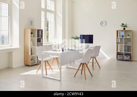 Interieur des modernen Bürozimmers mit großem Tisch, modernen Stühlen und Desktop-Computer Stockfoto