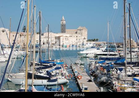 Einige Boote dockten im Hafen von Trani und der Schöne mittelalterliche Kathedrale am Meer im Hintergrund in einem Klar blau sonnigen Sommertag Stockfoto