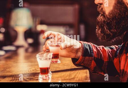 Tequila-Schuss. Trinken von Alkohol in Schnapsgläser in einem Nachtclub oder einer Bar. Bärtiger Mann Schüsse Cocktail. Tequila Shots, Wodka, Whisky, Rum Stockfoto