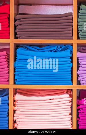 Holzschrank mit verschiedenen Farben Kleidung in einem Bekleidungsgeschäft zu zeigen. Stockfoto
