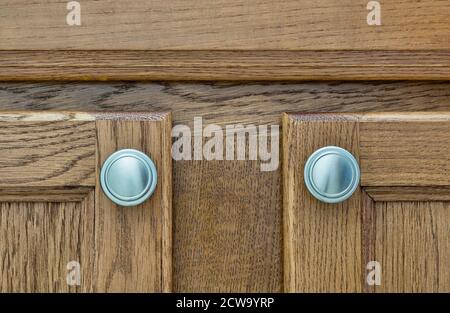 Braune Holzschranktüren mit silbernen Griffen Nahaufnahme, Holzfleck Farbmuster. Stockfoto