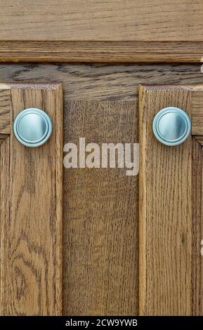 Braune Schranktüren aus Holz mit silbernen Griffen aus der Nähe, Farbmuster aus Holz im vertikalen Format. Stockfoto