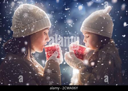 Glücklich liebende Familie! Mutter und Kind Mädchen trinken Tee auf verschneiten Winterspaziergang in der Natur. Frost Wintersaison. Stockfoto