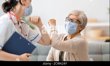 Arzt und ältere Frau mit Gesichtsmasken während des Coronavirus- und Grippeausbruchs. Virenschutz. COVID-2019. Masken übernehmen. Stockfoto