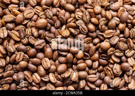 Geröstete arabica-Kaffeebohnen, in loser Schüttung auf einem Holztisch. Stockfoto