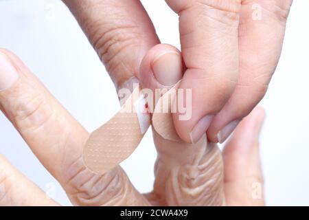 Krankenschwester, die eine klebende Bandage auf die Hand einer älteren Frau legt Stockfoto