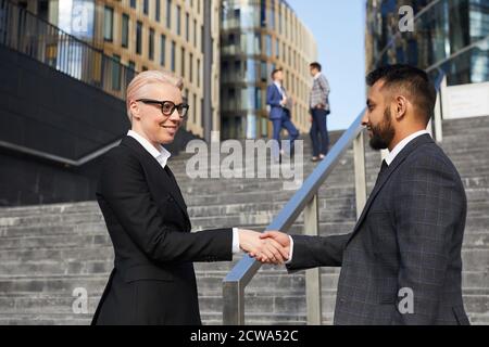 Geschäftspartner, die sich in der Stadt die Hände schütteln, begrüßen sich gegenseitig Stockfoto