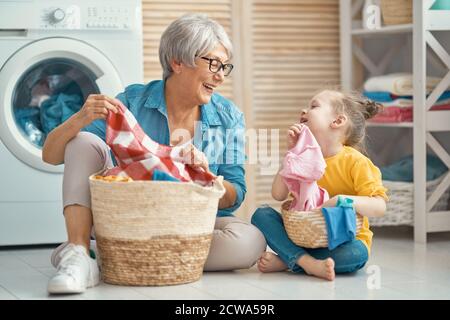 Glückliche Oma und Kind Mädchen kleinen Helfer haben Spaß und lächeln, während die Wäsche zu Hause. Stockfoto