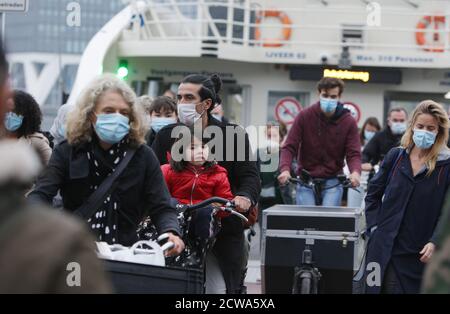 Die Einheimischen bekommen Gesichtsmasken auf den Fahrrädern, die am 28. September 2020 in Amsterdam, Niederlande, von einer kostenlosen Fähre am Fluss IJ inmitten der Coronavirus-Pandemie aussteigen. Der Premierminister Mark Rutte wird heute in der Nacht eine Pressekonferenz abhalten, um bekannt zu geben, welche Maßnahmen zur Bekämpfung der Ausbreitung des Virus insbesondere in den drei großen Städten Amsterdam, Rotterdam und Den Haag ergriffen werden, wo die Infektionen zunehmen. Amsterdam und Den Haag gehören zu den 10 Städten mit den meisten positiven Coronavirus-Fällen pro Kopf der Bevölkerung in Europa, die Liste wird von Paris angeführt, mit 231 Fällen pro 100,000 Einwohner und Amsterdam IS Stockfoto