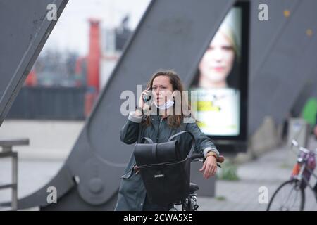 Eine Frau legt die Gesichtsmaske herunter, um am 28. September 2020 in Amsterdam, Niederlande, auf ihrem Handy an der Zentralstation zu sprechen. Der Premierminister Mark Rutte wird heute in der Nacht eine Pressekonferenz abhalten, um bekannt zu geben, welche Maßnahmen zur Bekämpfung der Ausbreitung des Virus insbesondere in den drei großen Städten Amsterdam, Rotterdam und Den Haag ergriffen werden, wo die Infektionen zunehmen. Amsterdam und Den Haag gehören zu den 10 Städten mit den meisten positiven Coronavirus-Fällen pro Kopf der Bevölkerung in Europa, die Liste wird von Paris angeführt, mit 231 Fällen pro 100,000 Menschen und Amsterdam ist i Stockfoto