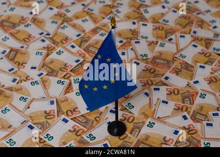 Viele 50-Euro-Banknoten sind über den Boden verteilt, auf dem eine europäische Flagge angebracht ist. Stockfoto