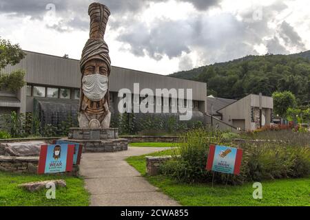 Cherokee, North Carolina, USA - 12. August 2020: Großer Totem Pole im Museum des Cherokee Indianers mit Gesichtsmaske zur Prävention von COVID 19. Stockfoto