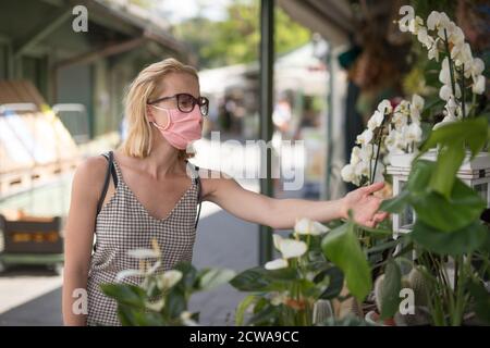 Lässige Frau, die an Marktständen im Freien einkaufen, tragen Fase-Masken zum Schutz vor einer Corona-Virus-Pandemie in München Stockfoto