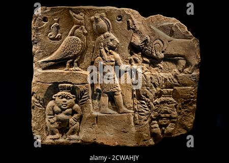 Terrakotta-Plakette mit Relief des Zwerggottes Bes, des Falkengottes Horus und der Löwengöttin Sechmet aus dem ptolemäischen Ägypten im Allard Pierson Museum Amsterdam. Terrakotta-Plakette mit Reliefs von Bes und anderen Gottheiten (4. – 1. Jahrhundert v. Chr.) aus der Spätzeit bis zur ptolemäischen Zeit. Das mehrteilige Relief zeigt den beliebten Schutzgott Bes, eine löwenköpfige Göttin (wahrscheinlich Sechmet oder Tefnut), einen heiligen Falken als Darstellung des Horus, eine Kobra-Uraeus und einen liegenden Stier. Es ist dauerhaft in den Sammlungen des antiken Ägyptens im Allard Pierson Museum in Amsterdam ausgestellt. Stockfoto
