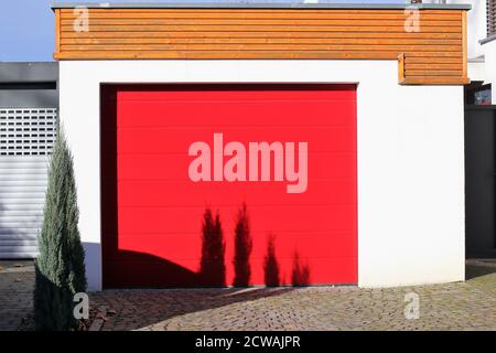 Hochwertiges rotes Garagentor (Sektionaltor) Neben einem Wohnhaus Stockfoto