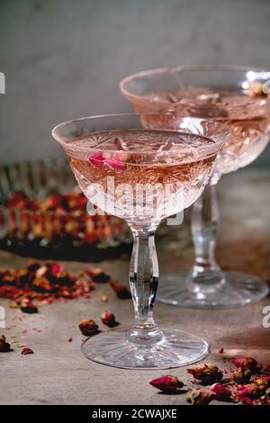 Kristall Vintage Gläser rosa Rose Champagner, Cider oder Limonade mit trockenen Rosenblüten. Hintergrund mit grauer Textur. Stockfoto