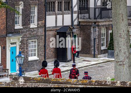 Drei Soldaten der Coldstream Guards und zwei Yeoman Warders vor dem Queen's House, im Tower of London, London EC3 Stockfoto