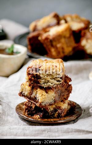 Trend Backen Brookies Schokolade Brownies und Kekse hausgemachte Kuchen von Quadraten in verschiedenen Keramikplatten geschnitten, Schokolade Sauce, Holzlöffel auf gr Stockfoto