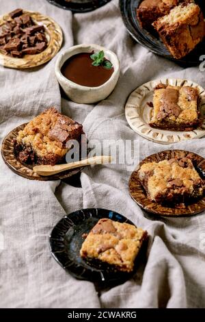 Trend Backen Brookies Schokolade Brownies und Kekse hausgemachte Kuchen von Quadraten in verschiedenen Keramikplatten geschnitten, Schokolade Sauce, Holzlöffel auf gr Stockfoto