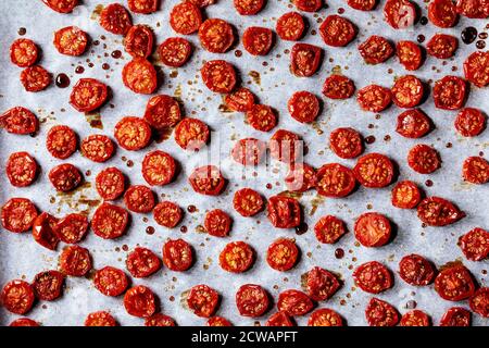 Sonnengetrocknete Kirschtomaten mit Olivenöl und Balsamico-Essig auf Backpapier. Draufsicht, Hintergrund Essen Stockfoto