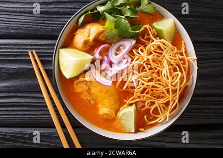 Kokosnuss-Curry-Suppe mit Huhn, gebratenen Nudeln und Gewürzen. Thai-Stil. Nahaufnahme horizontal von oben Stockfoto