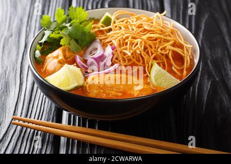 Khao Soi ist ein cremiges, leicht würziges gelbes Curry-Nudelgericht, das in Nordthailand in der Schüssel auf dem Tisch zu finden ist. Horizontal Stockfoto