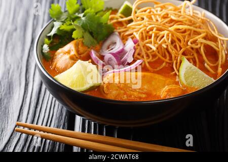 Kokosnuss-Curry-Suppe mit Huhn, gebratenen Nudeln und Gewürzen. Thai-Stil. Nahaufnahme horizontal Stockfoto